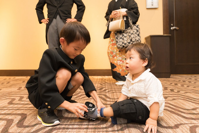 小さい子の靴を履かせる子ども