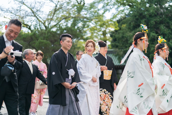 笑顔で花嫁行列をする新郎新婦