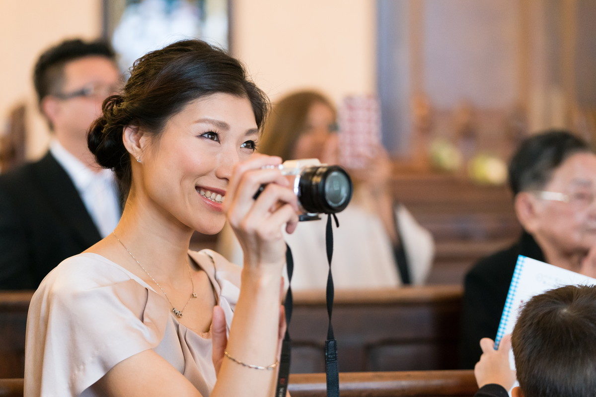 写真を撮りながら笑顔で祝福する花嫁お姉さん