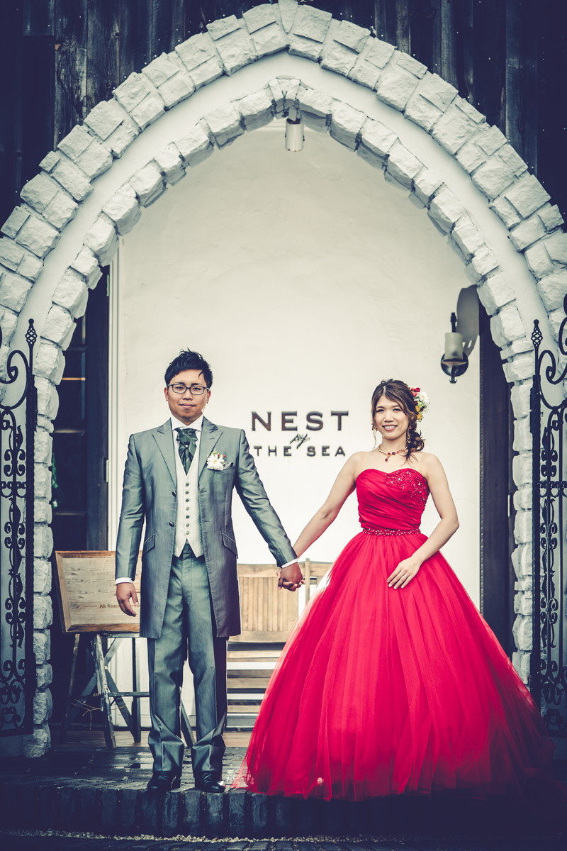 「NEST by THE SEA」さんのエントランス前で手をつなぐ新郎新婦