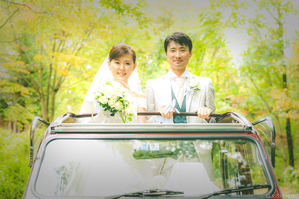 花嫁車に乗って笑顔の新郎新婦